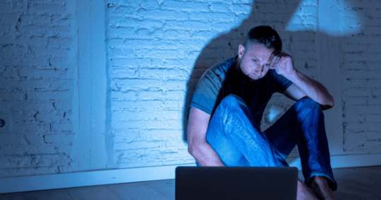 Man sitting in the dark looking at the computer